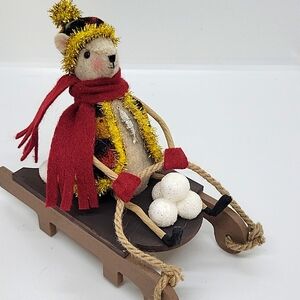 Felt bear riding a sled